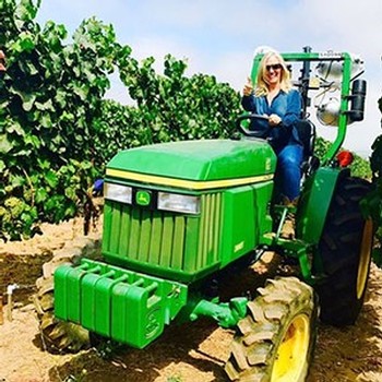 Woman in vineyard on green tractor